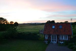 una pequeña casa con techo rojo en un campo en Hönshuset Kullabygden en Höganäs