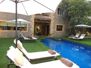 a pool with chairs and umbrellas next to a house at Villa Vallmar in Valldemossa