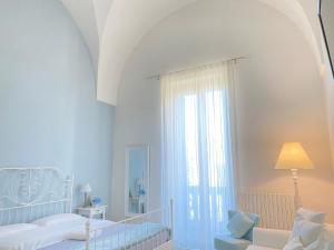ein weißes Schlafzimmer mit einem Bett und einem Fenster in der Unterkunft Alla Luce del Barocco in Lecce