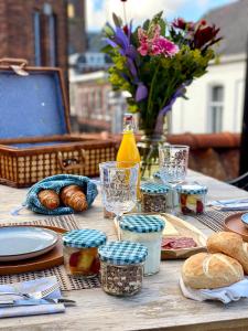 een tafel met eten en brood en een vaas met bloemen bij B&B Gasthuisstraat Dokkum in Dokkum