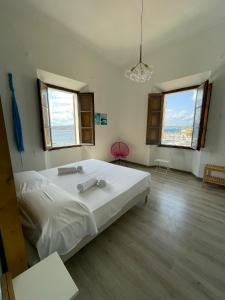 a bedroom with a large white bed and two windows at La Siesta in La Maddalena