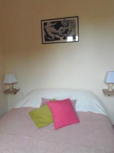 a bed with a pink and green pillow on it at Les Cimaises du Couvent in Beaune