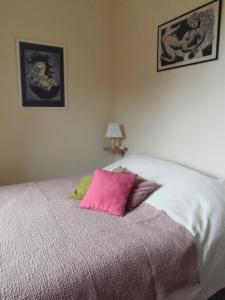 Una cama con dos almohadas rosas encima. en Les Cimaises du Couvent en Beaune