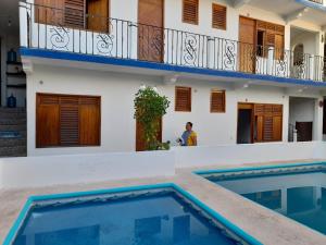 un uomo in piedi di fronte a una casa con piscina di Hotel Naxhiely a Puerto Escondido