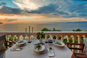 a table on a balcony with a view of the ocean at Paxos Sunrise Villas in Gaios