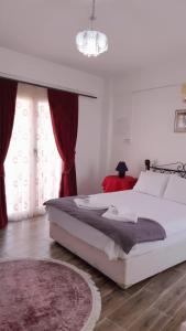 a bedroom with a large white bed with red curtains at Malia Holiday Let in Famagusta