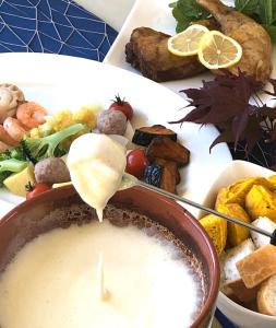 a plate of food with a bowl of dipping sauce at Auberge Ninguruforet in Biei