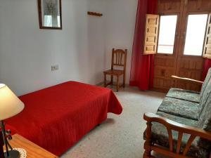 1 dormitorio con 1 cama roja y 1 silla en Apartamento rural Boreal en Cómpeta