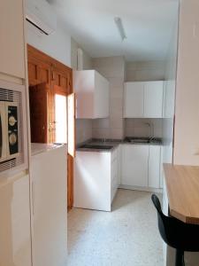 cocina con armarios blancos y nevera blanca en Apartamento rural Boreal en Cómpeta