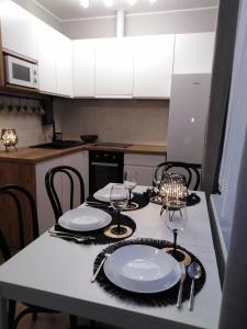 a kitchen with a table with plates and wine glasses at Apartament JOANNA in Sanok