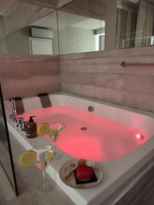 un bagno con vasca rosa, torta e bicchieri da vino di il sogno di afrodite luxury b and b a Roma