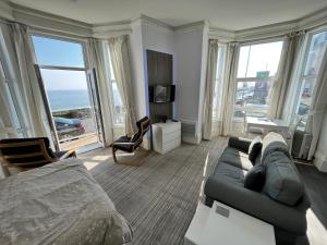 a living room with a bed and a couch and windows at Beaconsfield Holiday Apartments in Bridlington