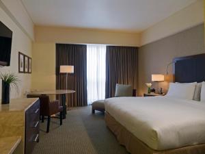 a hotel room with a large bed and a table at Grand Fiesta Americana Queretaro in Quer&eacute;taro