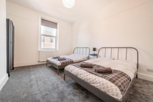 2 camas en un dormitorio con ventana en Peaky blinders apartment 5 min walk to Blackpool tower sleeps up to 14, en Blackpool