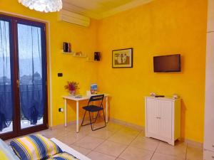 a yellow room with a table and a tv at B&B Maison Villa Vittorio in Avella