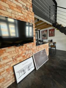a brick wall with a flat screen tv and some drawings at OFF Side Story Apartment in Łódź
