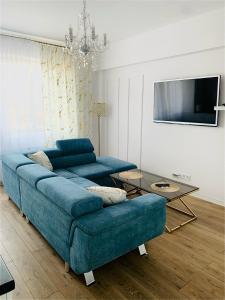 a living room with a blue couch and a table at KORONA Apartamenty Gdańsk in Gdańsk