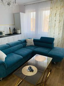 a living room with a blue couch and a glass table at KORONA Apartamenty Gdańsk in Gdańsk