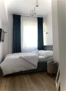 a bedroom with a bed with blue curtains and a window at KORONA Apartamenty Gdańsk in Gdańsk