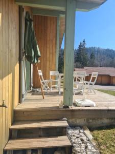 a porch with chairs and an umbrella on a house at Le repaire du Lynx in Bellefontaine