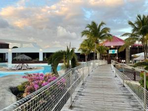 a wooden walkway leading to a pool at a resort at Ti Coco Location - Manganao Saint-François avec Citerne Tampon Automatique in Saint-François
