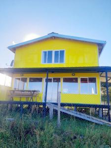 a yellow house with a picnic table in front of it at Hostal y Cabañas Mozart in Puerto Montt