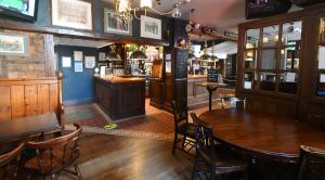 pub z drewnianym stołem i krzesłami oraz bar w obiekcie Tenby House w mieście Tenby
