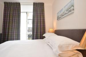 a bedroom with a bed and a window with curtains at Tenby House in Tenby