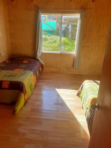 a bedroom with two beds in a room with a window at Hostal y Cabañas Mozart in Puerto Montt
