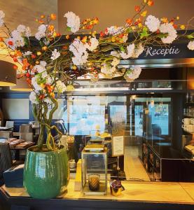 a vase with flowers on a counter in a restaurant at Logies Graaf Van Vlaanderen in Bruges