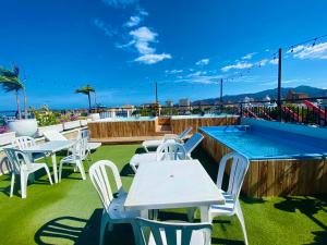 a patio with white tables and chairs and a swimming pool at Hotel Parque de los Novios Inn in Santa Marta