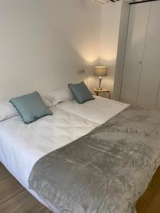 a large white bed with two blue pillows on it at Loft Manuel de Falla in Maracena