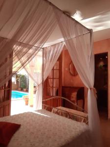 ein Schlafzimmer mit einem Himmelbett und einem Pool in der Unterkunft Agréable chambre d'hôtes, SDB, piscine, carbet cuisine. in Saint-Claude