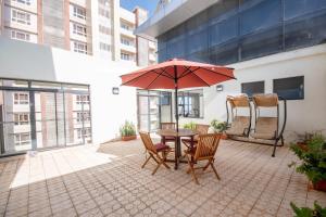 a patio with a table and chairs and an umbrella at Modern luxury one bedroom furnished apartment in Kilimani, Nairobi, Kenya in Nairobi