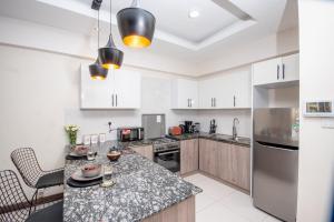 a kitchen with white cabinets and a granite counter top at Modern luxury one bedroom furnished apartment in Kilimani, Nairobi, Kenya in Nairobi