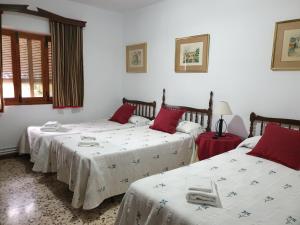 a bedroom with two beds with red and white sheets at Casa Rural Sole in Ossa de Montiel