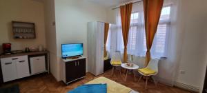 Una sala de estar con un televisor y una mesa y sillas. en Happy Mood Apartments, en Brasov