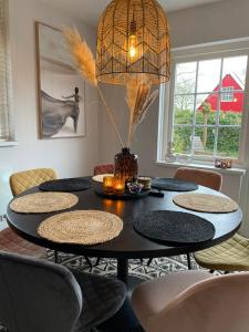 a room with a table with chairs and a chandelier at Heerlijk Huisje Achterhoek in Lievelde