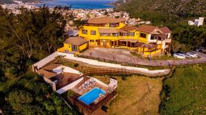 an overhead view of a large yellow house with a swimming pool at Sentinelas do Mar in Arraial do Cabo