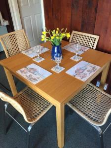 drewniany stół z krzesłami i wazon kwiatów w obiekcie No 27 A dog friendly rural coastal chalet w mieście Seaton