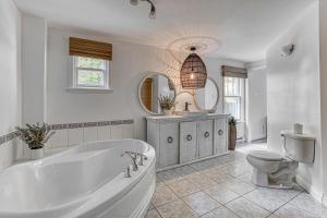 a white bathroom with a tub and a toilet at MOWEB - CHALET BORD DE L'EAU AVEC PLAGE iLE ORLEANS in Saint-Laurent-de-l'ile d'Orleans