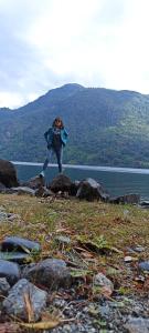 a woman standing on some rocks near a body of water at Casa de campo Llifén Futrono Lago Ranco in Ranco