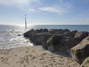 a beach with rocks and a pole in the water at Little Heaven self-catering caravan in Church Farm Holiday Park in Pagham