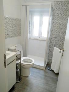 La salle de bains blanche est pourvue d'une douche et de toilettes. dans l'établissement Sol e praia, à Nazaré