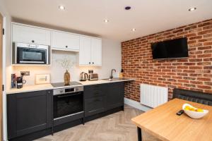 uma cozinha com armários pretos e uma parede de tijolos em Modern finish to a historic brewers house, Derby em Derby