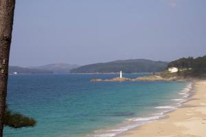 a view of a beach with a lighthouse in the distance at Hotel Playa de Lago in Muxia