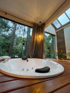 a bath tub sitting on a wooden table with windows at Pousada Vale das Orquídeas in Lavrinhas