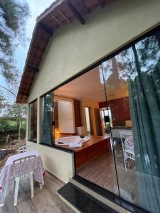 a house with a large window and a bath tub at Pousada Vale das Orquídeas in Lavrinhas