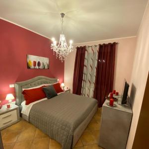 Un dormitorio con una cama con paredes rojas y una lámpara de araña. en CASA VACANZA FELICITA' en Porto Potenza Picena