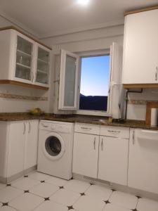 a kitchen with a washing machine and a window at Laredo primera línea de playa,zona puerto deportivo in Laredo